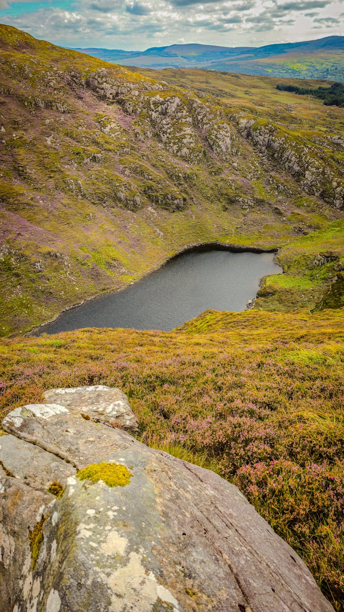 A breathtaking view of a serene mountain lake surrounded by lush hills in Croaghaun, Ireland.
